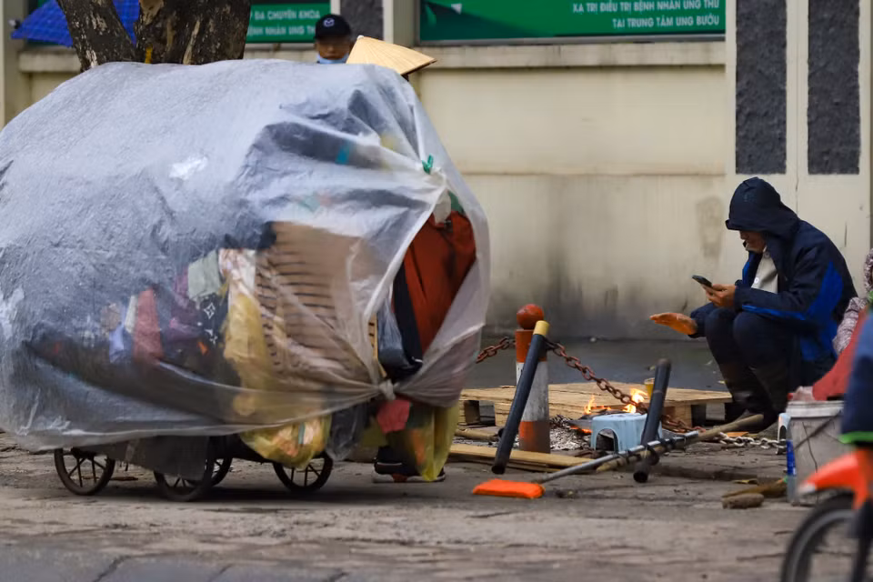 Nhiều người lao động không chịu nổi cái rét đã phải nhóm lửa ngay trên vỉa hè để sưởi ấm. (Ảnh: Hoài Nam/Vietnam+)