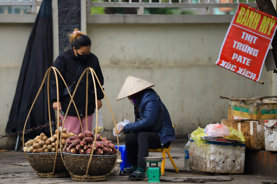 Bà Lan, một người bán hàng trước cổng bệnh viện K cơ sở 3 cho biết chỉ mong đợt lạnh này sớm qua để... có khách. "Rét quá, hàng hóa ế ẩm, tay chân thì tê bì hết cả," bà nói. (Ảnh: Hoài Nam/Vietnam+)