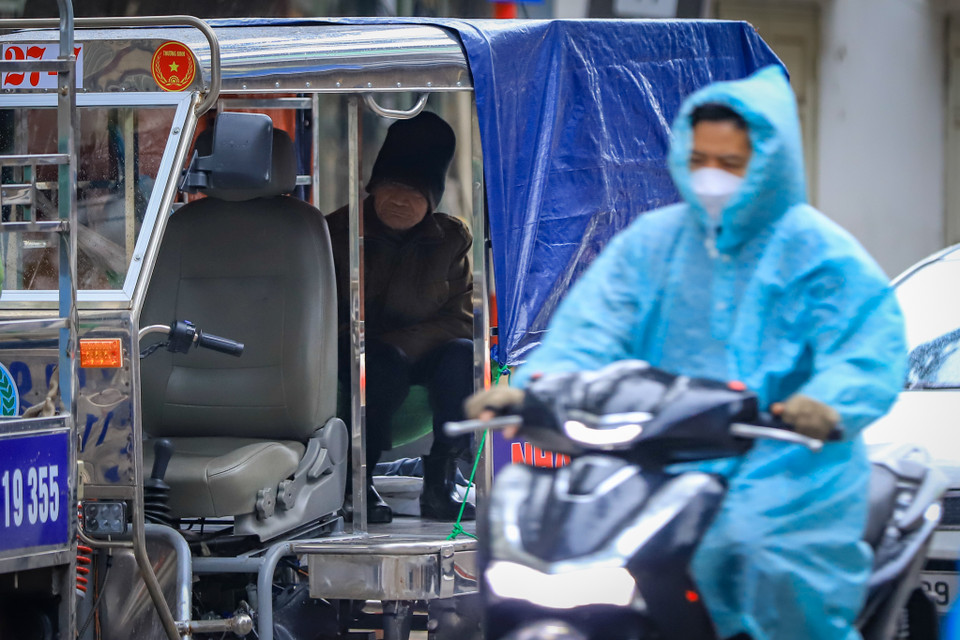 Những người có việc ra đường cũng phải mặc kín nhất có thể. Một chiếc áo mưa, đôi găng tay làm cho cơ thể ấm hơn đôi chút. (Ảnh: Hoài Nam/Vietnam+)