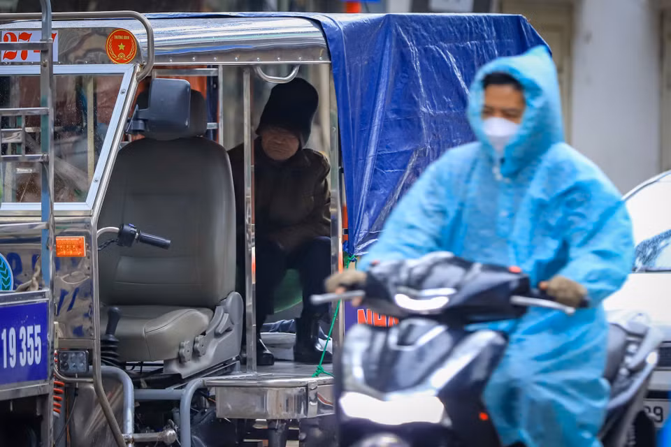 Những người có việc ra đường cũng phải mặc kín nhất có thể. Một chiếc áo mưa, đôi găng tay làm cho cơ thể ấm hơn đôi chút. (Ảnh: Hoài Nam/Vietnam+)