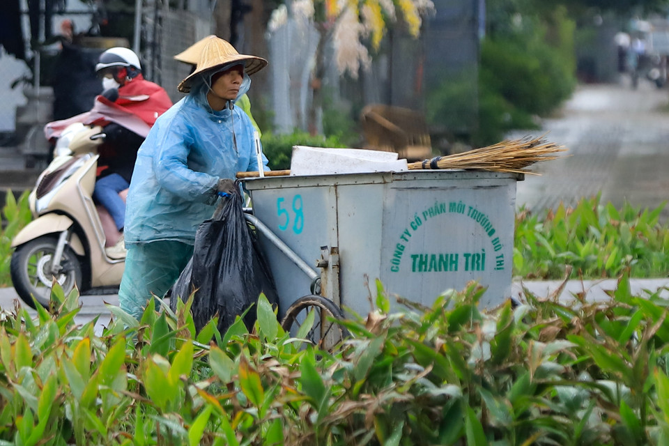 Một công nhân vệ sinh môi trường co ro dưới cái lạnh chỉ 7 độ C, cần mẫn với công việc làm sạch đường phố. (Ảnh: Hoài Nam/Vietnam+)