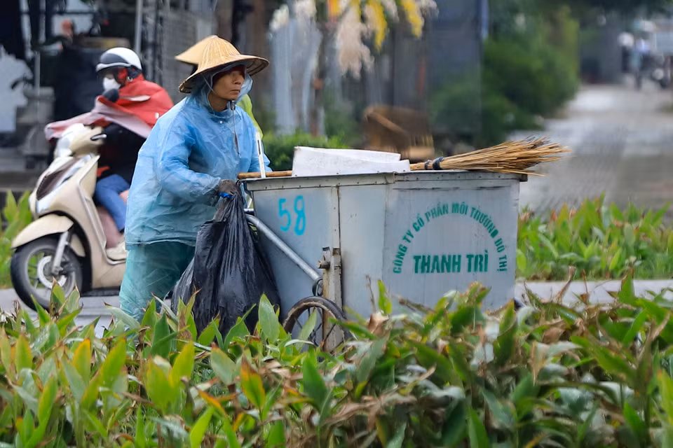 Một công nhân vệ sinh môi trường co ro dưới cái lạnh chỉ 7 độ C, cần mẫn với công việc làm sạch đường phố. (Ảnh: Hoài Nam/Vietnam+)
