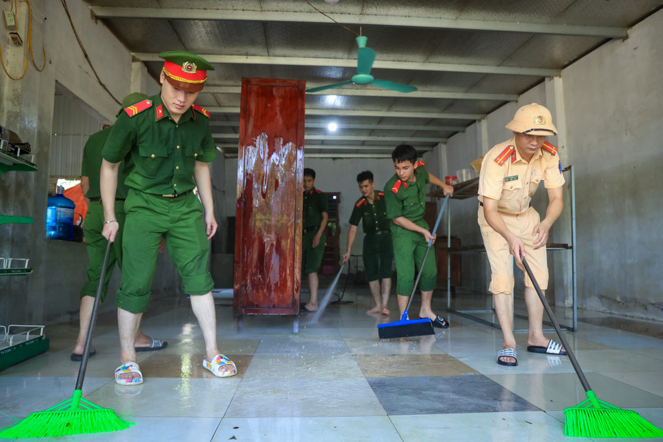 Lực lượng công an hỗ trợ bà con vệ sinh nhà cửa, tẩy rửa để sớm ổn định lại cuộc sống sau trận ngập lụt vừa qua. (Ảnh: Hoài Nam/Vietnam+)