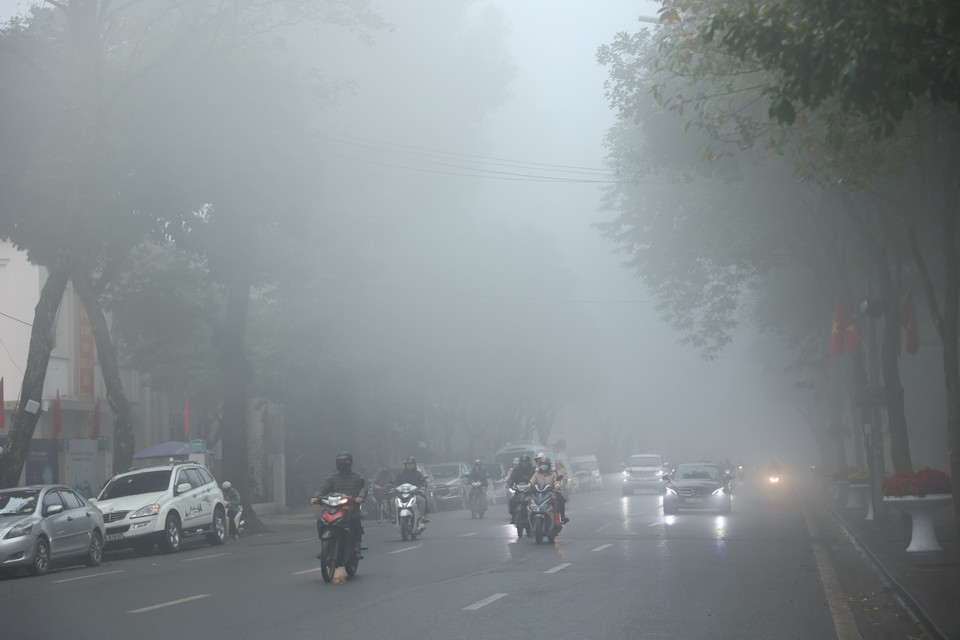 Trên nhiều tuyến phố, phương tiện di chuyển chậm, phải bật đèn vì tầm nhìn hạn chế. (Ảnh: Hoài Nam/Vietnam+)