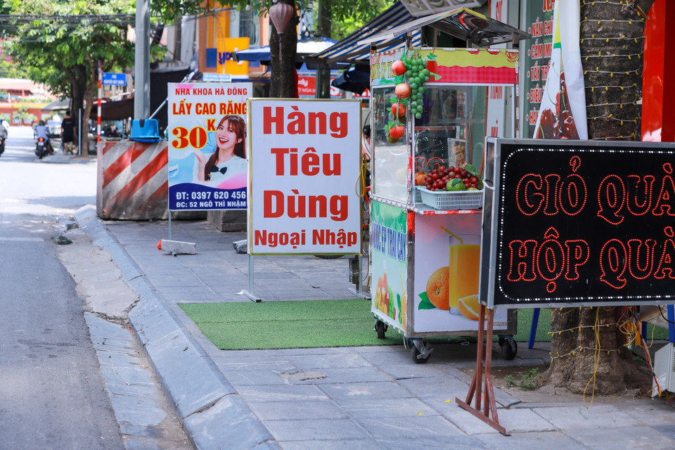 Tại một tuyến phố ở Hà Đông, các cửa hàng bày hàng hóa và biển quảng cáo chiếm trọn vỉa hè. (Ảnh: Hoài Nam/Vietnam+)