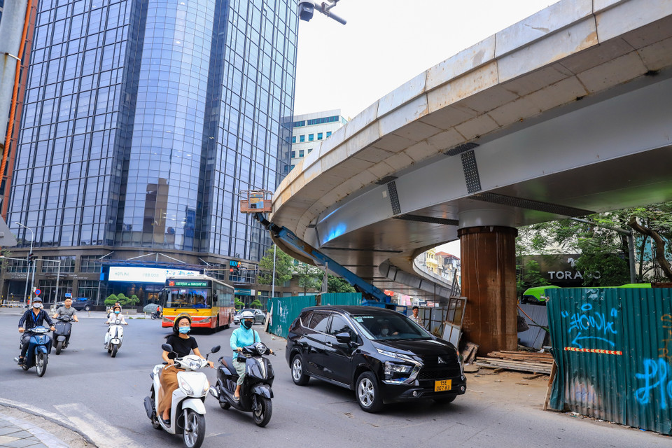 Phần phía dưới cầu, công nhân cũng đang tháo dần các rào chắn bằng tôn, hoàn trả mặt đường, đồng thời hoàn thiện phần mố cầu, bờ bo và lan can. (Ảnh: Hoài Nam/Vietnam+)