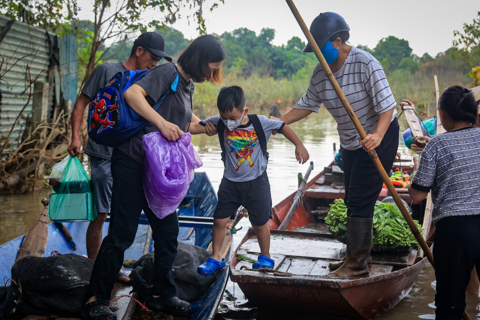 Chị Hà cho biết ngày trước cho con đi học mất 15-20 phút nhưng giờ gia đình phải dậy trước cả tiếng để di chuyển bằng thuyền trên con đường độc đạo từ bãi giữa về ngõ 76 An Dương đang chìm trong dòng nước. (Ảnh: Hoài Nam/Vietnam+)