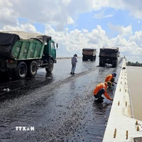 Thi công trải thảm nhựa nóng mặt cầu Đại Ngãi 2, ngày 4/5. (Ảnh: Trung Hiếu/TTXVN)