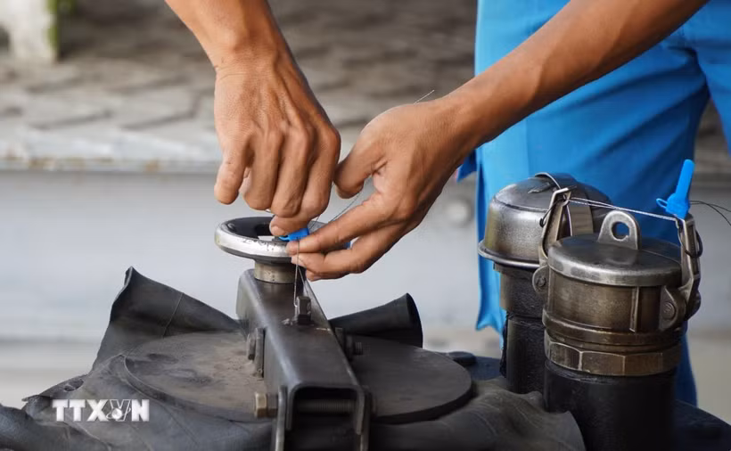 Nhân viên của Petimex Đồng Tháp thực hiện kẹp chì niêm phong hàng trước khi đi giao cho khách hàng. (Ảnh minh họa: Nhựt An/TTXVN)