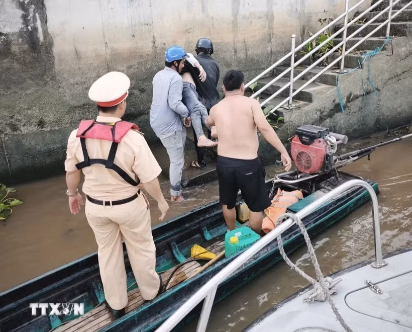 Cán bộ, chiến sỹ Cảnh sát đường thủy số 2 phối hợp đưa nạn nhân từ xuồng máy lên bờ để sơ cứu, chuyển đến cơ sở y tế cấp cứu. (Ảnh: TTXVN phát)