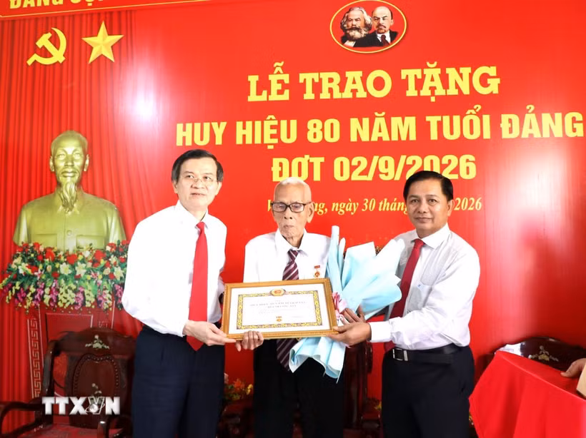 Đoàn công tác trao Huy hiệu 80 năm tuổi Đảng và hoa chúc mừng đảng viên Huỳnh Long Tòa, xã Cầu Ngang. (Ảnh: Thanh Hòa/TTXVN)