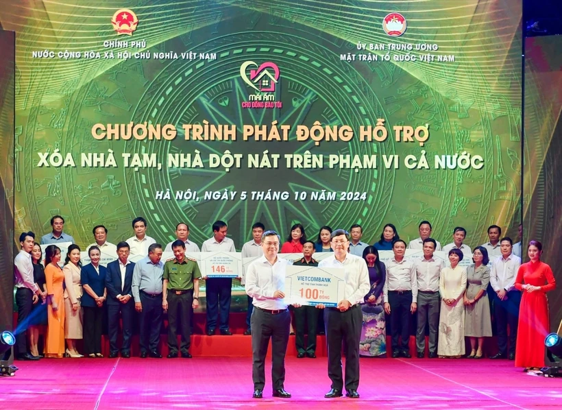 Ông Nguyễn Thanh Tùng (bên trái) - Bí thư Đảng ủy, Chủ tịch HĐQT Vietcombank trao tượng trưng kinh phí 100 tỷ đồng hỗ trợ xoá nhà tạm, nhà dột nát ủng hộ cho địa phương. (Ảnh: Vietnam+)