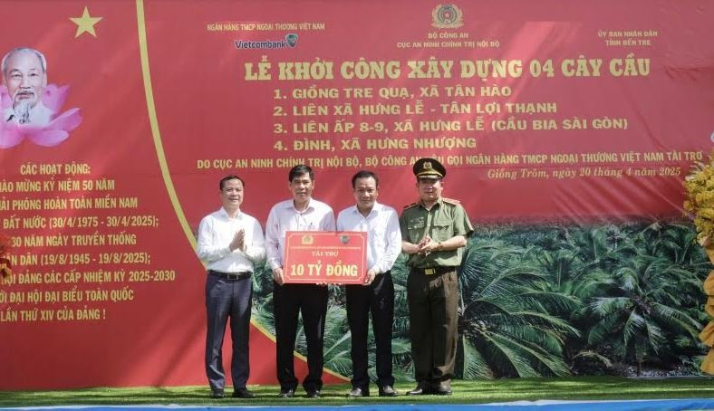 Thiếu tướng Đinh Văn Nơi - Cục trưởng Cục An ninh chính trị nội bộ, Bộ Công an (ngoài cùng bên phải) và ông Lê Hoàng Tùng – Phó Tổng Giám đốc Vietcombank (ngoài cùng bên trái) trao bảng tượng trưng số tiền tài trợ xây dựng 4 cầu giao thông nông thôn tặng huyện Giồng Trôm, tỉnh Bến Tre. (Ảnh: Vietnam+)
