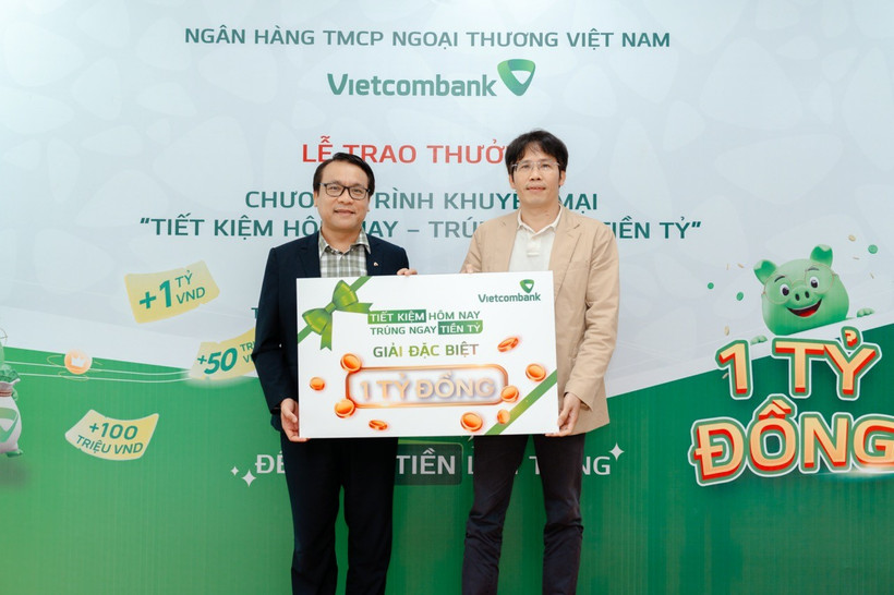Anh Quang Nam (bên phải) nhận giải đặc biệt trị giá 1 tỷ đồng trong chương trình “Tiết kiệm hôm nay - Trúng ngay tiền tỷ” tại Vietcombank chi nhánh Tân Bình. (Ảnh: Vietnam+)