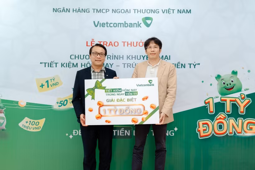 Anh Quang Nam (bên phải) nhận giải đặc biệt trị giá 1 tỷ đồng trong chương trình “Tiết kiệm hôm nay - Trúng ngay tiền tỷ” tại Vietcombank chi nhánh Tân Bình. (Ảnh: Vietnam+)