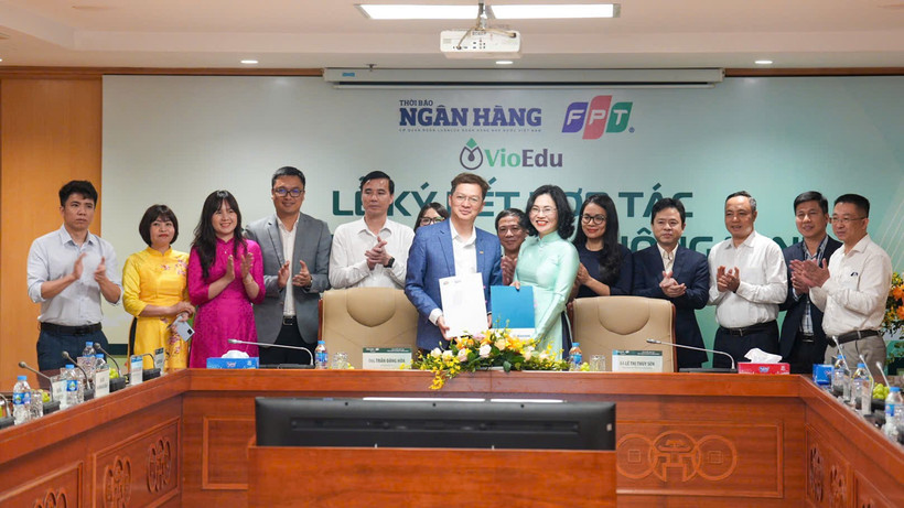 Đại diện Thời báo Ngân hàng và đại diện Tập đoàn FPT trao biên bản hợp tác. (Ảnh: Vietnam+)