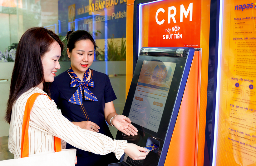 Nhân viên SHB hướng dẫn khách hàng sử dụng máy CRM. (Ảnh: Vietnam+)