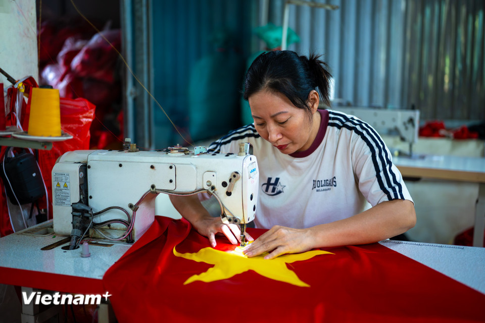 Từng phiến vải đỏ rực rỡ cùng những mảnh sao vàng lấp lánh lần lượt được những người thợ lành nghề cắt, ghép, sẵn sàng khơi dậy niềm tự hào dân tộc trên khắp mọi miền đất nước. (Ảnh: Minh Sơn/Vietnam+)