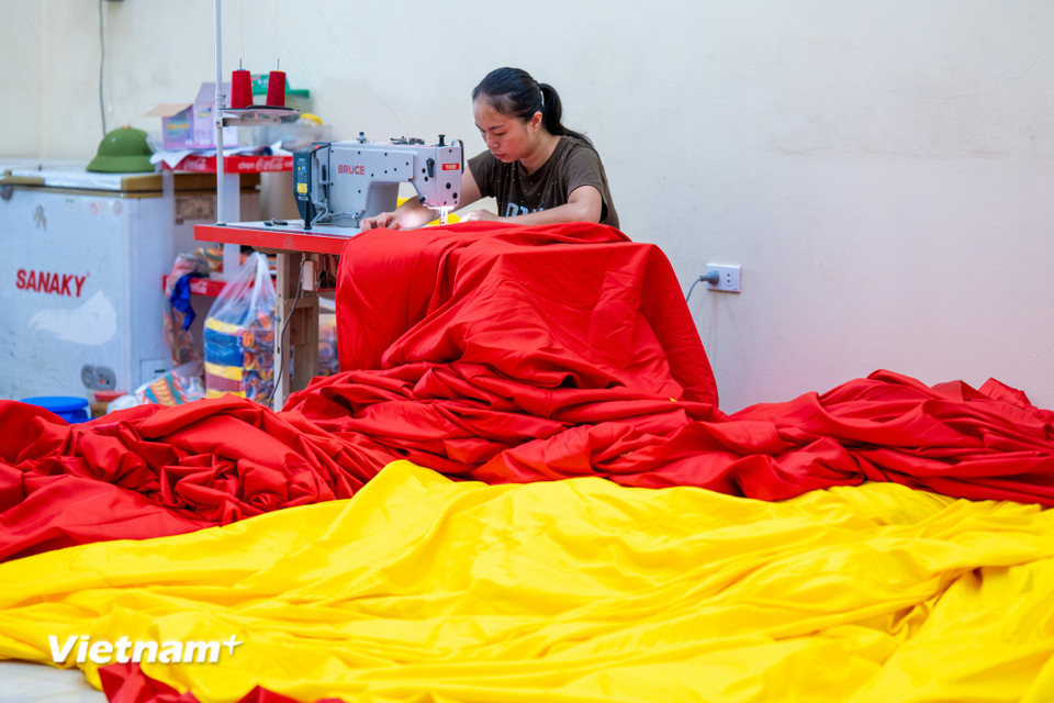 "Năm nay là dịp đặc biệt, kỷ niệm 50 năm Giải phóng miền Nam và 80 năm Quốc khánh, đơn hàng tăng xưởng tôi gấp rưỡi so với ngày thường. Nhiều tỉnh, thành và các đơn vị tổ chức sự kiện ngoài trời, tại biển đảo, hay các giải chạy phong trào đều đặt cờ với số lượng lớn. Năm nay có một đơn vị tổ chức sự kiện ở Hà Nội gần đến dịp Quốc khánh 2/9 đã đặt một lá cờ Tổ quốc khổng lồ diện tích lên tới 600m2," anh Trung tiết lộ. (Ảnh: Minh Sơn/Vietnam+)