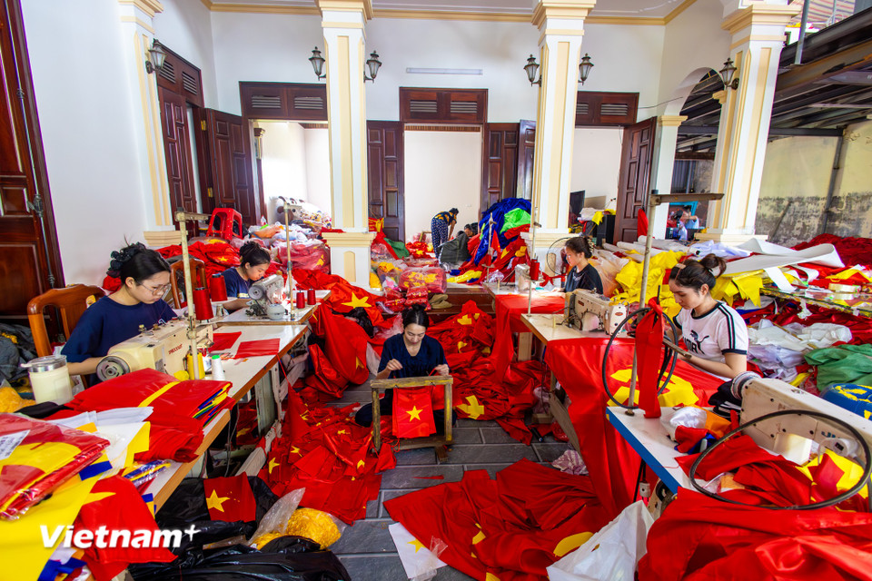 Càng gần tới ngày Quốc khánh 2/9, không khí tại làng Từ Vân (xã Chương Dương, Hà Nội) lại càng trở nên khẩn trương và rộn rã. Từ sáng sớm, những dãy xưởng may nối tiếp nhau mở máy, từng mũi chỉ, từng nét thêu, từng đường cắt vải đỏ sao vàng được thực hiện liên tục trong ánh đèn, tiếng động cơ và tiếng trò chuyện khẩn trương của các công nhân. (Ảnh: Minh Sơn/Vietnam+)