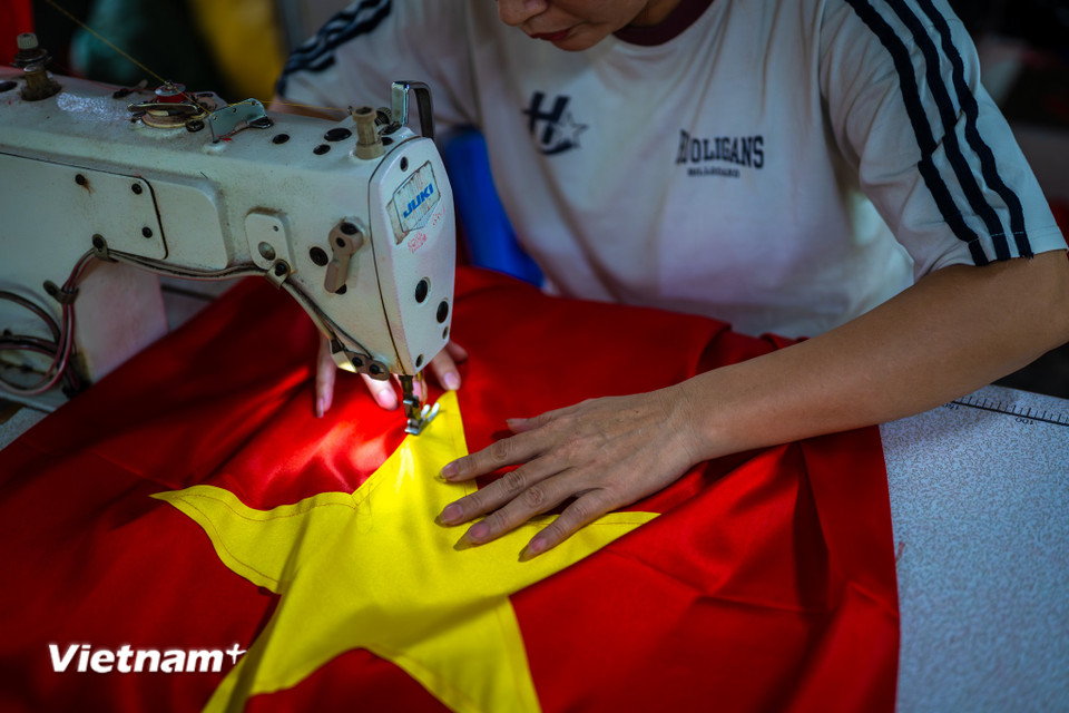 Anh Nguyễn Văn Trung là thế hệ thứ ba giữ gìn nghề truyền thống may cờ gia đình. Từ khi tiếp quản cơ sở, anh đã mở rộng quy mô lên đến 15 thợ lành nghề, mỗi ngày cho ra lò gần 1.000 lá cờ đủ kích cỡ, từ những lá cờ cầm tay nhỏ xíu đến các đại kỳ treo ở quảng trường, sân bay. (Ảnh: Minh Sơn/Vietnam+)