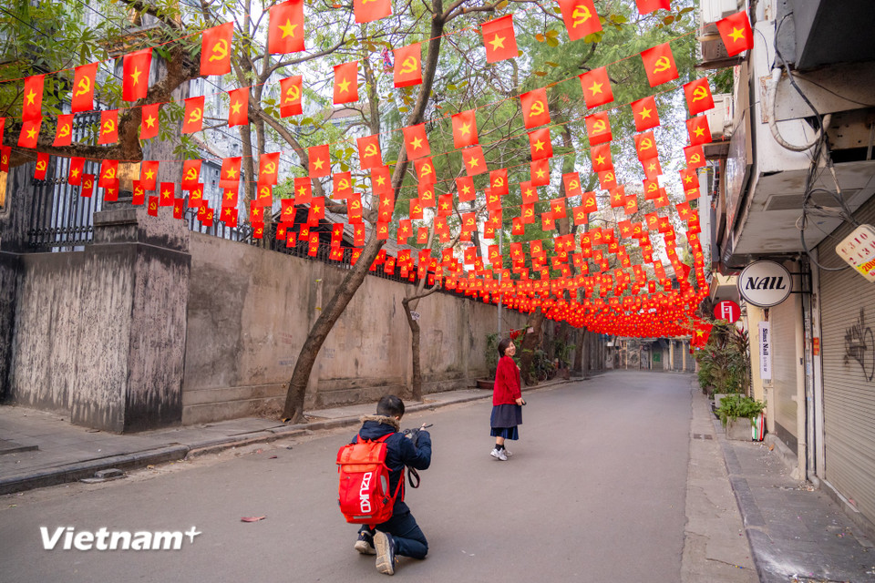 Ai ai cũng muốn có cho mình một bức hình lưu niệm thật đẹp ngày đầu tiên của năm mới tại con phố Ấu Triệu rực rỡ cờ đỏ sao vàng. (Ảnh: Minh Sơn/Vietnam+)