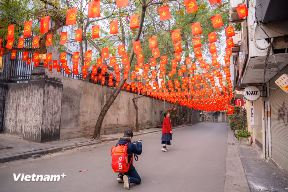 Ai ai cũng muốn có cho mình một bức hình lưu niệm thật đẹp ngày đầu tiên của năm mới tại con phố Ấu Triệu rực rỡ cờ đỏ sao vàng. (Ảnh: Minh Sơn/Vietnam+)