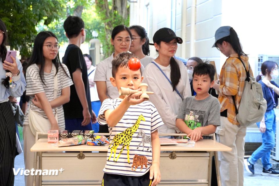Trẻ em thích thú thử sức với Kendama, trò chơi rèn sự khéo léo và kiên nhẫn của Nhật Bản. (Ảnh: Nguyễn Tâm/Vietnam+)