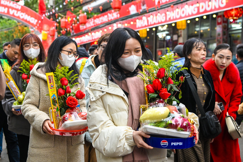 Nhiều người mặc nguyên trang phục công sở, tay cầm hương hoa, lễ vật thành kính dâng lên cửa Phật, mong một năm mới bình an, tài lộc. (Ảnh: Minh Sơn/Vietnam+)
