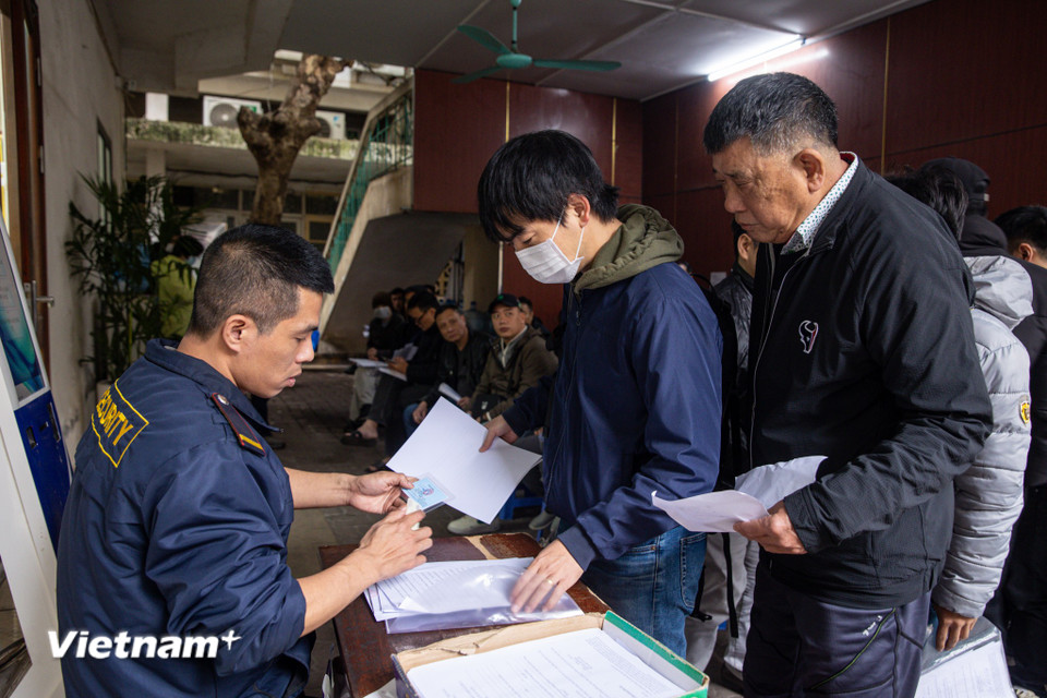 Người dân xếp hàng lấy số thứ tự để làm thủ tục. Sau khi nhận số thứ tự, người dân điền vào mẫu đơn được phát tại bộ phận một cửa. (Ảnh: Minh Sơn/Vietnam+)