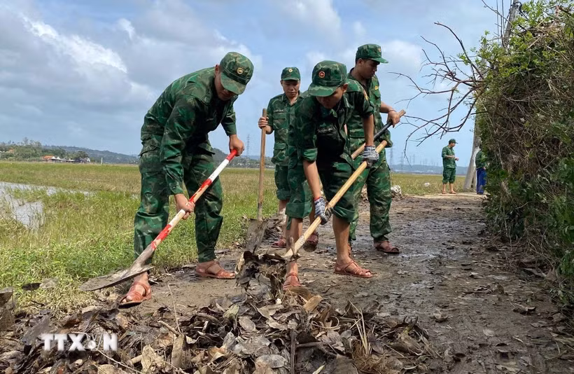 Cán bộ, chiến sỹ Đồn Biên Phòng Tuy Hòa dọn bùn đất tại phường Phú Yên để người dân đi lại thuận tiện. (Ảnh: Tường Quân/TTXVN)