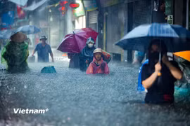 Người dân Thủ đô bì bõm lội nước dưới cơn mưa cực lớn trong ngày 30/9/2025. (Ảnh: Hoài Nam/Vietnam+)