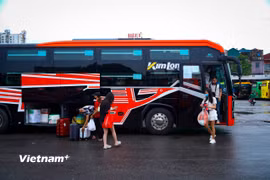 Hành khách đón xe khách tại bến xe. (Ảnh: PV/Vietnam+)