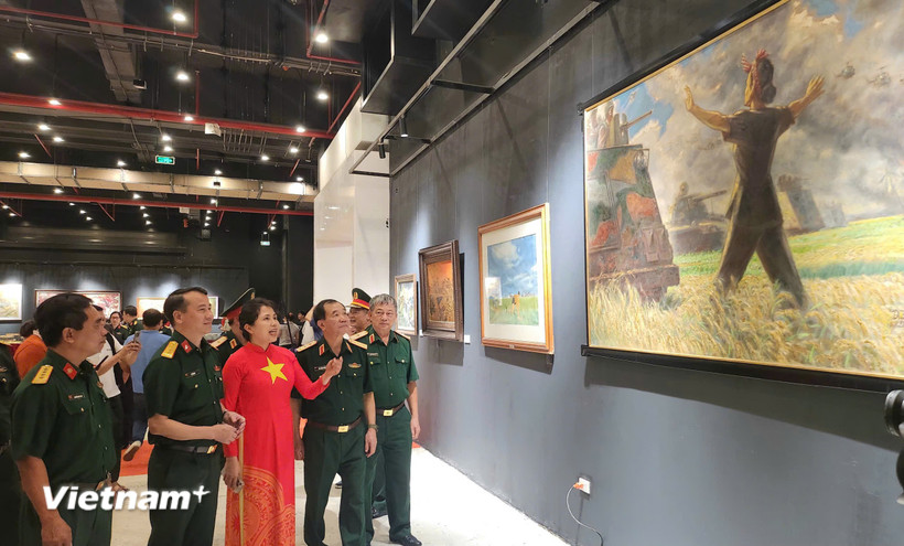 Họa sỹ Nguyễn Thu Thủy cùng các đại biểu tham quan triển lãm. (Ảnh: Minh Thu/Vietnam+)