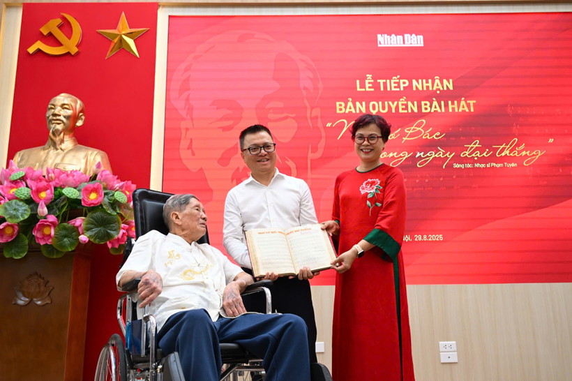 Tổng Biên tập Lê Quốc Minh nhận bản thảo bài hát "Như có Bác trong ngày đại thắng" có chữ ký đề tặng của nhạc sỹ Phạm Tuyên. (Ảnh: CTV/Vietnam+) 