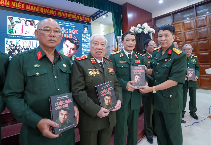 Đại tá Đặng Vương Hưng tặng tác phẩm “Cuộc đời còn mãi” cho các cựu chiến binh. (Ảnh: PV/Vietnam+)