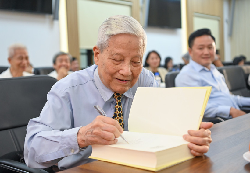 Nhà báo Hà Đăng ký tặng tại Lễ ra mắt sách. (Ảnh: PV/Vietnam+)