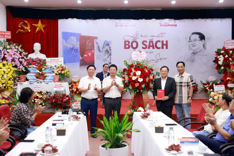 Ông Trần Thanh Lâm, Phó Trưởng Ban Tuyên giáo và Dân vận Trung ương và Tổng Biên tập Báo Tiền Phong Phùng Công Sưởng tặng hoa chúc mừng tác giả Lê Xuân Sơn (thứ hai từ phải sang). (Ảnh: Như Ý/Vietnam+)