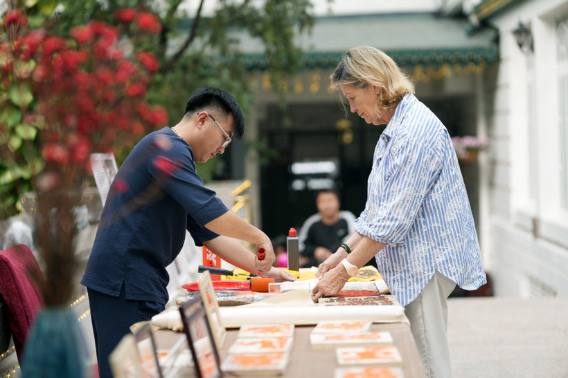 Nghệ nhân hướng dẫn du khách in mộc bản liễn. (Ảnh: CTV/Vietnam+)
