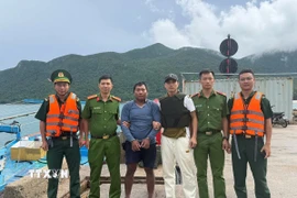 Lực lượng chức năng tiếp cận, tiến hành bắt giữ Trần Văn Phúc lẩn trốn trên tàu cá BT 92907 TS và dẫn giải đối tượng vào bờ. (Ảnh: TTXVN phát)
