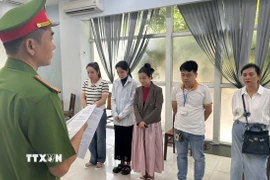 Lực lượng chức năng đọc lệnh Khởi tố tại Phòng khám Đa khoa Quốc tế Đà Nẵng. (Ảnh: TTXVN phát)