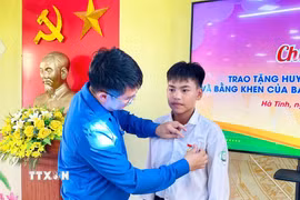 Trao tặng Huy hiệu "Tuổi trẻ dũng cảm" cho em Chu Văn Tuấn Vũ. (Ảnh: TTXVN phát)