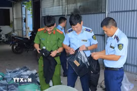 Lực lượng chức năng kiểm tra các sản phẩm may mặc giả mạo các nhãn hàng lớn. (Ảnh: Đức Phương/TTXVN)