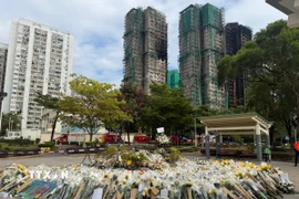 Hàng nghìn bông hoa được người dân mang đến gần hiện trường vụ cháy để bày tỏ niềm thương tiếc với các nạn nhân. (Ảnh: Mạc Luyện/TTXVN)