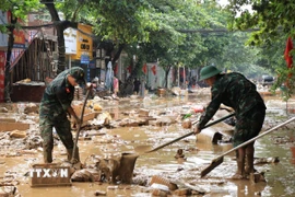 Cán bộ, chiến sỹ Bộ chỉ huy Quân sự tỉnh Lào Cai giúp đỡ người dân vùng ngập lụt khắc phục hậu quả. (Ảnh: Đinh Thùy/TTXVN)