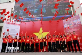 Người dân Thủ đô lưu lại kỷ niệm những khoảnh khắc ý nghĩa cùng lá cờ Tổ quốc và bản tin đặc biệt tại trụ sở TTXVN. (Ảnh: Nhật Anh/TTXVN)