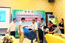 Tiến sỹ Võ Anh Khuê (thứ 3, bên trái sang) hướng dẫn sử dụng thùng ủ rác có thể tích 220 lít cho người dân ở thị trấn Phú Phong, huyện Tây Sơn, tỉnh Bình Định. (Ảnh: Vusta)