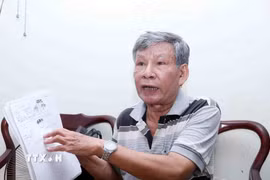 Ông Nguyễn Văn Tâm với cuốn sổ ghi chép mô tả địa hình qua những lần thực địa tìm hài cốt đồng đội. (Ảnh: Xuân Khu/TTXVN)