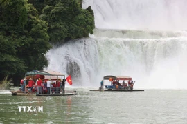 Du khách Việt Nam mang theo cờ Tổ quốc tham quan Khu hợp tác du lịch xuyên biên giới Thác Bản Giốc (Việt Nam)-Đức Thiên (Trung Quốc). (Ảnh: Công Tuyên/TTXVN)