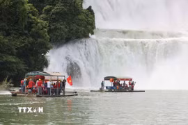 Du khách Việt Nam mang theo cờ Tổ quốc tham quan Khu hợp tác du lịch xuyên biên giới Thác Bản Giốc (Việt Nam)-Đức Thiên (Trung Quốc). (Ảnh: Công Tuyên/TTXVN)